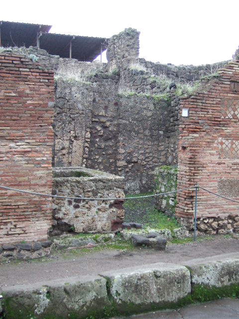 IX.1.13 Pompeii. December 2004. Looking east across counter with remains of hearth on north side of shop-room.
