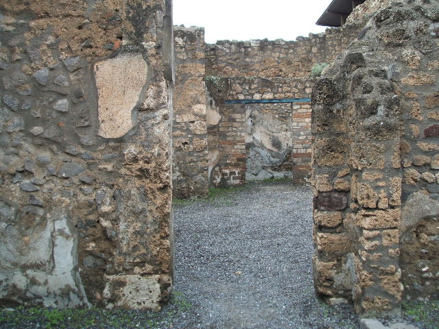 IX.1.18 Pompeii. December 2006. Looking north-east across yard towards site of kitchen, latrine and stairs to upper floor, in shadow. In the middle can be seen the doorway to the storeroom or cupboard.