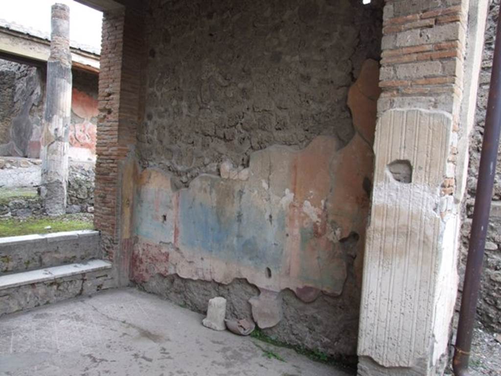 IX.1.22 Pompeii. December 2007. Room 7, east wall of tablinum. The walls of the tablinum were divided into sections, the centre of the dado (of the east wall) was painted white and dolphins were painted in two small panels, the side panels of the dado were painted purple.
In centre of the middle zone was a blue panel, with a red drape or curtain at the top.
Above the curtain was a naked figure in the centre. In the side panels on a yellow background were architectural paintings. The upper zone was yellow.
See Bragantini, de Vos, Badoni, 1986. Pitture e Pavimenti di Pompei, Parte 3. Rome: ICCD. (p.401, tablino ‘h’)