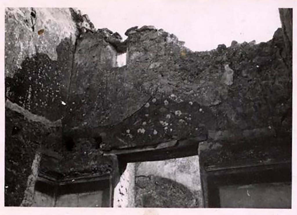 IX.2.7 Pompeii. Pre-1943. Room (i), upper south-east corner of the cubiculum. Photo by Tatiana Warscher.
See Warscher, T. Codex Topographicus Pompeianus, IX.2. (1943), Swedish Institute, Rome. (no.23.), p. 51.
According to Warscher –
“The holes for the support beams for a ceiling show that there was an upper floor, which received its light through a small window.
A stucco strip decorated the top of the ground floor room.
It was not possible to say what paintings decorated the centre of the side panels.”