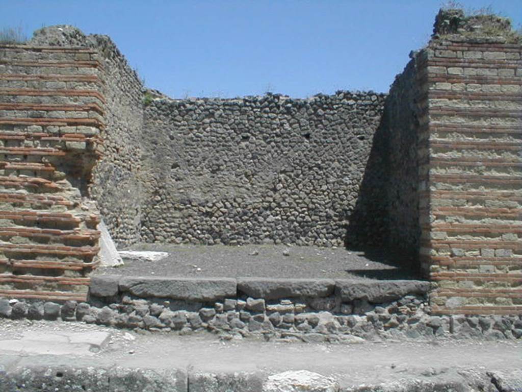 IX.4.2 Pompeii. May 2005. Looking east towards entrance on Via Stabiana.
According to Maiuri, three of the shops on the corner of this insula, appear to have had an elevated threshold of at least 0.80m above the floor of the sidewalk and what should have been the original threshold. They clearly distinguish the brickwork/masonry of the above elevation from the original floor of the threshold. In the third taberna (from the corner of the quadrivium) IX.4.3, only one block of the threshold appears located in its place.
See Maiuri, A, (2002): L�ultima fase edilizia di Pompei, Arte Tipografica, Naples, (p.75, note 3).


