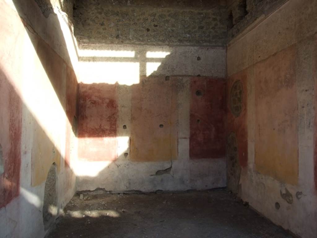 IX.5.11 Pompeii. December 2007. Room 3, looking east. The ala was decorated with red and yellow panels, in half of which were painted Cupids. Under the panels was a black zoccolo, and above them was a frieze finishing above with a stucco cornice. In the small panels of this frieze we see painted on the back (east) wall, a woman�s figure on foot, crowned with fronds and dressed in a green robe, holding a plate or basket in her left hand, and holding the lower edge of her robe with her right hand. On the wall to the right, was a Cupid with club, and under in small rectangles with purple backgrounds, one sees two fighters with daggers. On the wall to the left, finally we have another Cupid, that has in his right hand a bunch of grapes and in the left, an object that cannot be defined, below in a rectangle with purple background, one sees an open volume, on which were painted some black words, in part vanished and difficult to read. 
See Notizie degli Scavi, 1877, p.248

