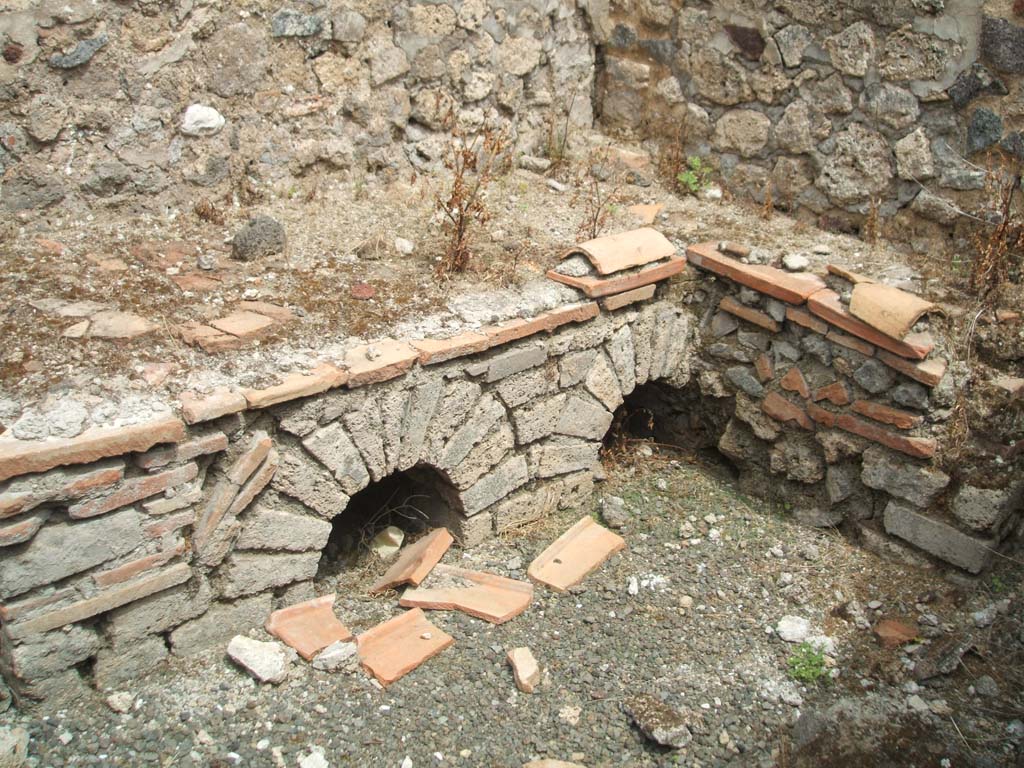 IX.5.14 Pompeii. May 2005. Room “q”, kitchen.
Looking north-east towards hearth in kitchen (room “q”), on south side of peristyle, in servants’ area.
According to Boyce, on the south wall of this kitchen, was a fragmentary lararium painting.
Boyce said that Mau thought this kitchen was reserved for the use of the members of the household.
See Boyce G. K., 1937. Corpus of the Lararia of Pompeii. Rome: MAAR 14. (p.86, no.426).
See Sogliano, A., 1879. Le pitture murali campane scoverte negli anni 1867-79. Napoli: (p.19, no.69)