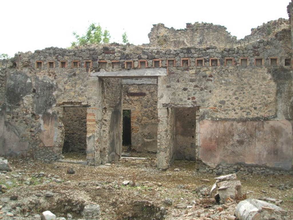 IX.5.18 Pompeii. May 2005. Looking south across atrium, room b, towards the entrance doorway, in centre. The doorway on the left leads into room h, which according to Zevi measured approximately 3.50m x 3.70m. It was the kitchen area with a latrine and masonry hearth. The walls were roughly plastered but on the left (east) wall was a simple decoration consisting of a yellow zoccolo, and red upper face to the walls.
See Zevi, F., 1964. La Casa Reg IX.5.18-21 a Pompei e le sue pitture: Studi Miscellanei 5. Roma: Bretschneider. (p.9 and note 22)