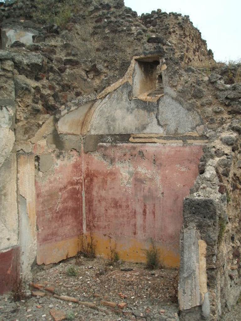 IX.5.18 Pompeii. May 2005. Room “n”, small room, or alcove on east side in north-east corner.
The walls of the alcove were painted with a yellow zoccolo with painted plants, the middle zone was painted with violet panels edged by a border and in the centre of the panel was a vignette of a cupid.
In the middle of the wall was a candelabra surmounted by a bird/eagle. The floor was raised.