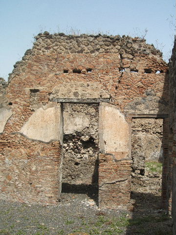 IX.6.3 Pompeii. May 2005. Doorway to kitchen area, looking south.
According to Boyce, on the east wall (not photographed) was a lararium painting, the upper part was damaged when found. An altar stood between the Genius on the right, and the tibicen on the left. On each side was a Lar with rhyton and situla standing between two shrubs. In the lower zone were two serpents confronted at an altar furnished with two eggs. See Boyce G. K., 1937. Corpus of the Lararia of Pompeii. Rome: MAAR 14. (p.86, no.428). See Sogliano, A., 1879. Le pitture murali campane scoverte negli anni 1867-79. Napoli: (p.12, no. 25) According to Giacobello, today the painting has been totally lost.
See Giacobello, F., 2008. Larari Pompeiani: Iconografia e culto dei Lari in ambito domestico. Milano: LED Edizioni. (p.209)