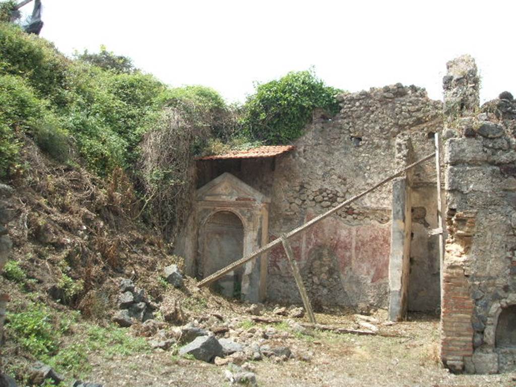 IX.6.8 Pompeii. May 2005. Looking towards west wall of garden area 9 with large aedicula lararium in south-west corner. In the north-west corner is a partition wall forming a cupboard/storeroom. The garden, entered directly from the atrium, occupied the south-west part of this small house. In the south-west corner of the garden stood a large aedicula niche lararium. The interior of the niche, coated with yellow stucco, had a painting of a leafy tree with birds flying around it. On the floor of the niche was a rectangular, stucco covered base, which Sogliano identified as an altar. Boyce identified it as a statue base decorated with a painted mask on the front.
See Jashemski, W. F., 1993. The Gardens of Pompeii, Volume II: Appendices. New York: Caratzas. (p.238)
According to Boyce, his reference was Not.Scavi, 1880, 231; Bull. Inst., 1882, 116.
See Boyce G. K., 1937. Corpus of the Lararia of Pompeii. Rome: MAAR 14. (p.87, no.432, and Pl.37,1)
According to Giacobello, aedicula on west wall of garden, today not conserved. It was of rectangular form opening into an arched niche decorated with a stucco shell. On the lower part, frescoed in yellow, were birds in flight, and a cherub with a double flute near to the depicted tree. Recovered from inside the niche, was an altar decorated with marble, and on the main side, was a tragic mask.
See Giacobello, F., 2008. Larari Pompeiani: Iconografia e culto dei Lari in ambito domestico. Milano: LED Edizioni. (p.286)