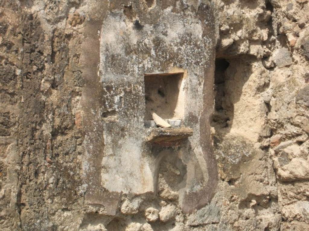 IX.7.21 Pompeii. May 2005. Square niche on west wall of atrium.
According to Boyce, in the north-west corner of the atrium was the hearth. Above the hearth in the west wall was a panel of white stucco. In the panel was a square niche. Its edges were outlined in red against the white background and below it was a cornice. On the reddish coloured back wall of the niche was painted a white object, which Mau was unable to identify. He did state that it was not a phallus. Below the niche was a painted garland of red and green leaves, and below it a burning altar with a pine-cone. On either side of the altar was a yellow serpent. The serpent on the left had a red crest and beard, the head of the other was damaged. See Boyce G. K., 1937. Corpus of the Lararia of Pompeii. Rome: MAAR 14. (p.88, no.441, and Pl.4, 4) According to Giacobello, the painting is no longer conserved. See Giacobello, F., 2008. Larari Pompeiani: Iconografia e culto dei Lari in ambito domestico. Milano: LED Edizioni. (p.250)