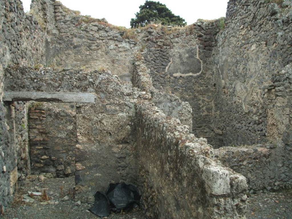 IX.9.9 Pompeii. May 2005. Looking south from corridor, towards doorway to light-yard (seen on upper right side). Through the doorway on the left, was an open courtyard garden area at the south of the corridor. At the rear of the doorway (on upper left-side) would be another room with a doorway from the open courtyard and with window into the courtyard on its west side. According to Eschebach, on the right was a kitchen with a window to the light-yard. At the rear was a windowed triclinium, and a courtyard garden.
See Eschebach, L., 1993. Geb�udeverzeichnis und Stadtplan der antiken Stadt Pompeji. K�ln: B�hlau. (p.442)
According to NdS, the room on the right would have been a narrow storeroom. The room in the upper left-rear side was a �mystery� room (stanza mistica) with a projecting window into the courtyard. In the courtyard was the doorway to the �mystery� room, on its external wall was seen the remains of a painting of a large serpent. In its north-west corner, and bricked into the pilaster, was a terracotta tub or basin ?
See Notizie degli Scavi, 1889, p.526

