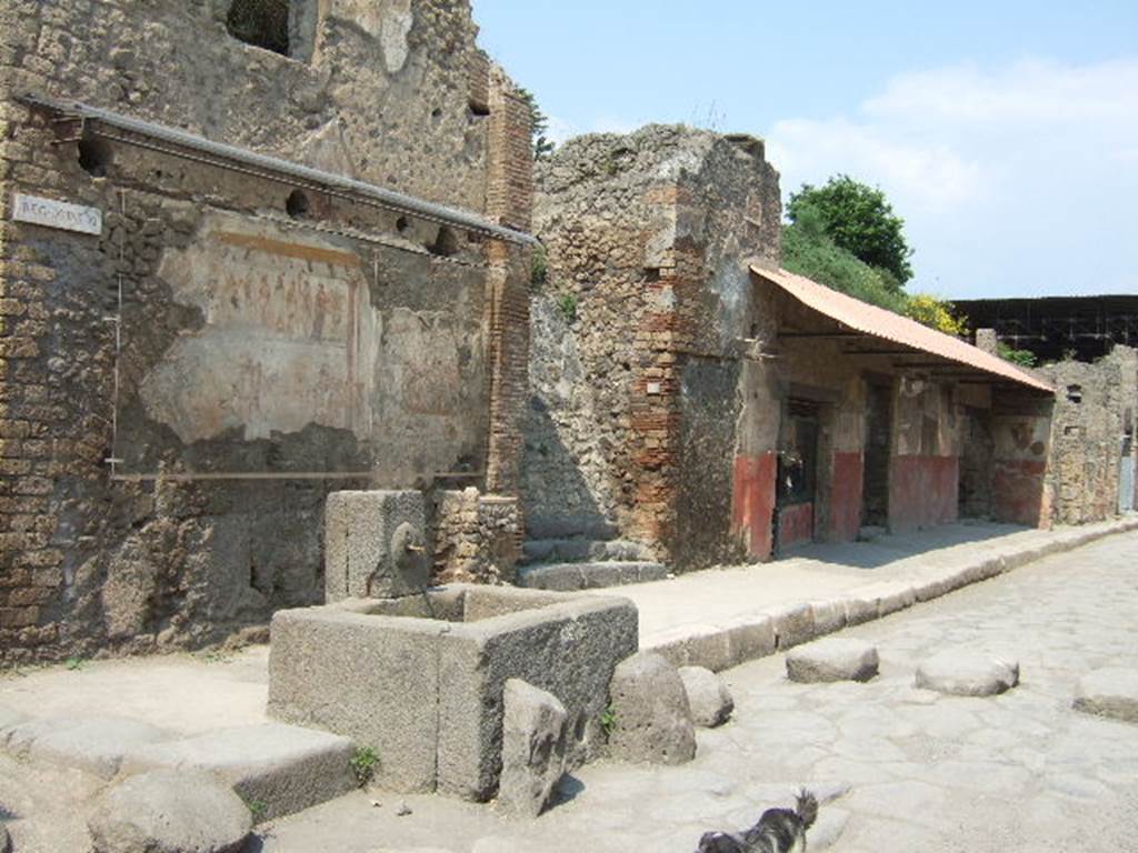 IX.11.1 Pompeii. May 2006. Looking north-east along Via dell�Abbondanza towards house with street shrine and fountain, left. and Thermopolium of Asselina, right. According to Della Corte, written on the street shrine above the altar with the last sacrifice in honour of the 12 gods, were the names of the Vicomagistri, reading  �
Successus, Victor
Asclepiades, Co(n)sta(n)s      (Vicomagistri)        [CIL IV 7855]
See Della Corte, M., 1965.  Case ed Abitanti di Pompei. Napoli: Fausto Fiorentino. (p.307)

