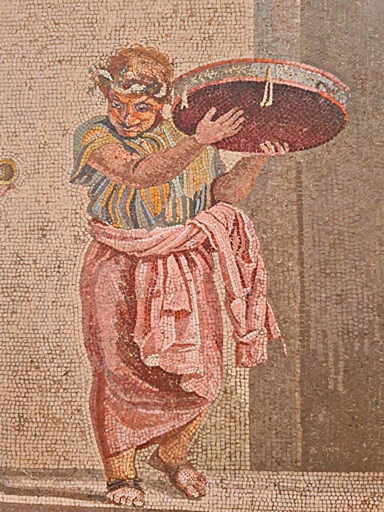 HGW06 Pompeii. Found on 8th April 1763. Ambiente 13 of Villa of Cicero.
Detail from mosaic of a Group of Street Musicians, musician with tambourine.
Now in Naples Archaeological Museum. Inventory number 9985.
Photo courtesy of Giuseppe Ciaramella. September 2024.