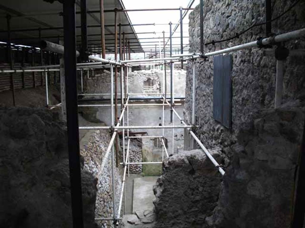 Unnamed Vicolo between IX.12 and IX.13. May 2010. Excavation behind IX.13.1.  Looking east from unnamed vicolo.  
According to Cerulli Irelli, “A work of excavation had been followed to isolate the humidity from the two splendid rear rooms of the said house (i.e. of IX.13.1/3 Julius Polybius), and the rustic quarters of a house has appeared to the north of this last house and presented a small kitchen with cupboard (repositorium) in a notable state of conservation, and a vast lararium picture with several elements on the rear wall of an uncovered/open room: this seemed to be evidence of plebeian art not inferior to the lararium picture found in the actual house of Julius Polybius.”
See Cerulli Irelli, G: Cronache Pompeiane, 2, (II), 1976, Notizario, attivita archeologica. (p.241). 
