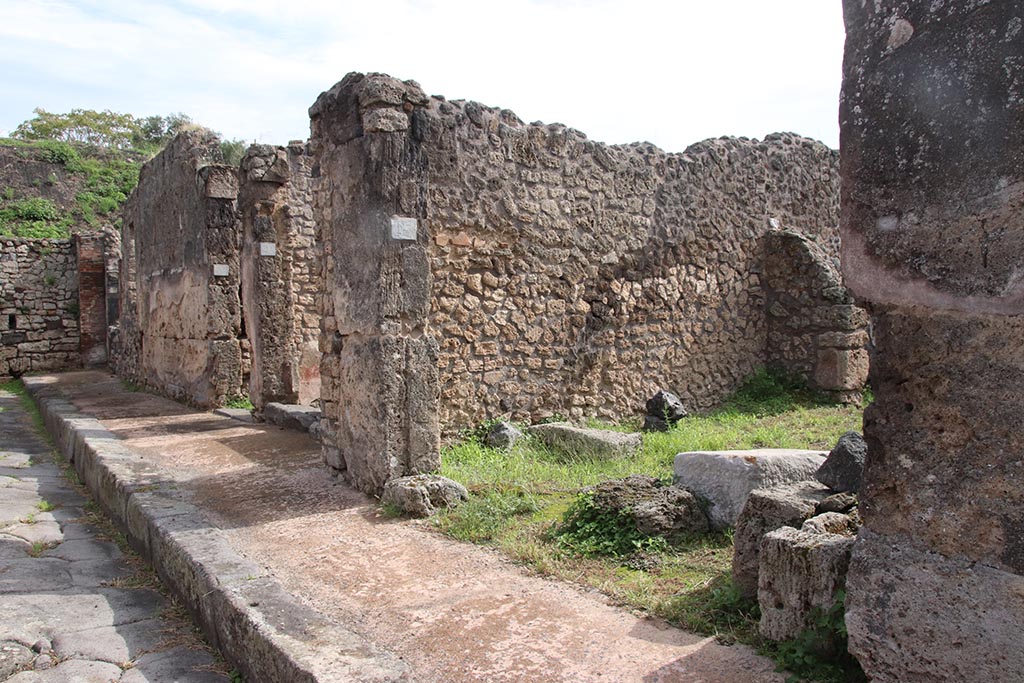 Unnamed vicolo between IX.6 and IX.7, Pompeii. October 2024. 
Looking south-east along entrance doorways on south side of roadway in IX.7. Photo courtesy of Klaus Heese.
