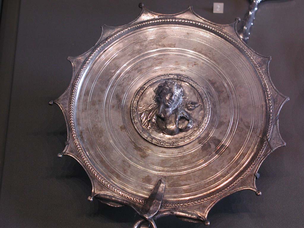 Villa della Pisanella, Boscoreale. Boscoreale silver hand mirror. In the center, in a medallion: bust of Bacchante.
According to De Villefosse, Mirror adorned with the bust of Ariadne and bearing the signature of the engraver M. Domitius Polygnos, with the indication of the weight of the piece.
Miroir � manche. Au centre, dans un m�daillon : buste de Bacchante.
Selon De Villefosse, Miroir orn� du buste d'Ariane et portant la signature du ciseleur M. Domitius Polygnos, avec l'indication du poids de la pi�ce.
Now in the Louvre, inventory number BJ2158.
De Villefosse H., 1902. L'argenterie et bijoux d'or du tr�sor de Boscoreale description des pi�ces conserv�es au Mus�e du Louvre - Monuments et Memories 5 1899 with supplement 1902, pl. XIX.

