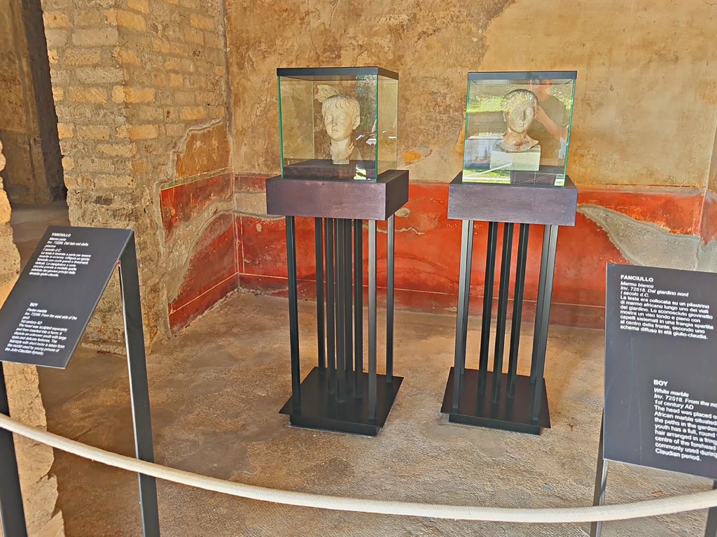 Oplontis Villa of Poppea, October 2023. 
Room 88, looking west through doorway from Portico 60, towards two marble heads of boys on display here.
The one on the left (inv. 73299) was found on the east side of the pool and the one on the right (inv. 72518) along one of the paths in the north garden. 
Photo courtesy of Giuseppe Ciaramella. 
